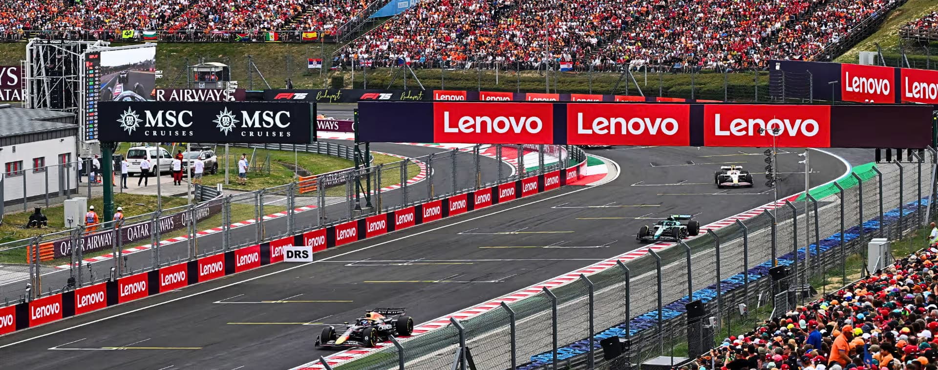 Formula 1 cars race along the Hungaroring straight between densely packed grandstands