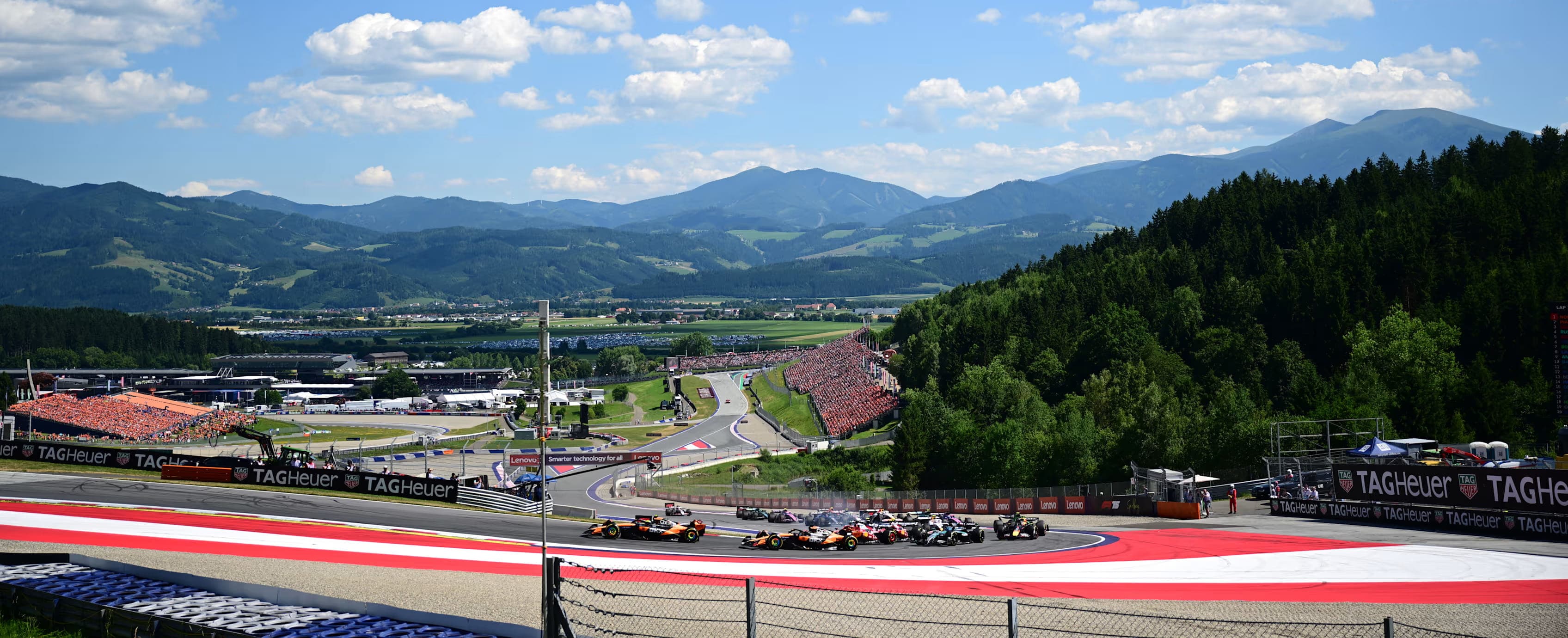 Formula 1 cars sweep through the Red Bull Ring with forested Styrian mountains filling the horizon