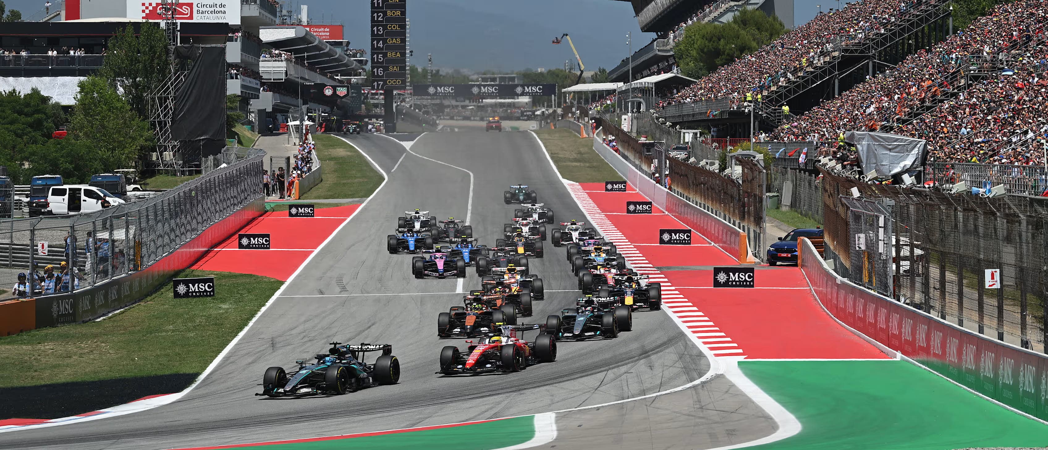 The Formula 1 field races down the main straight at Circuit de Barcelona-Catalunya in front of packed grandstands