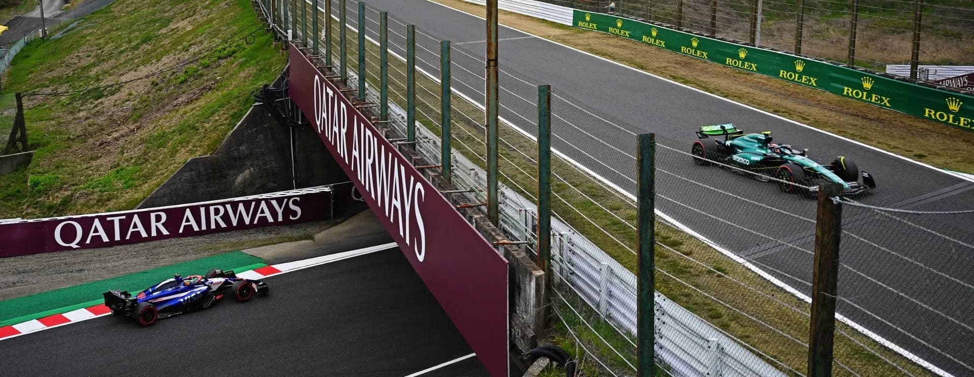 Two Formula 1 cars pass on different levels of Suzuka Circuit's figure-eight crossover